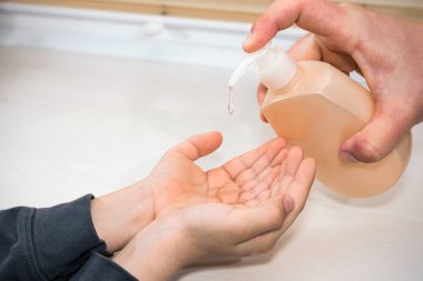 Yakın plan baba, şişe pompası dezenfektanı jel temizliği küçük çocuk COVID-19 veya koronavirüs koruma konsepti, fotokopi alanı ile.