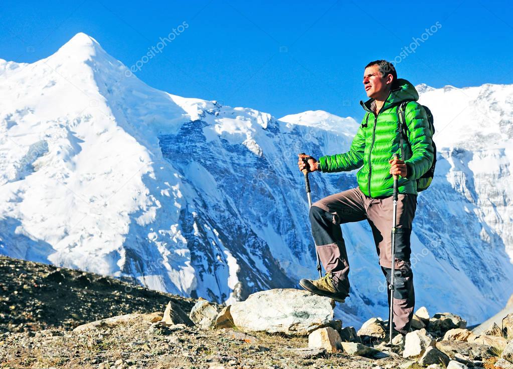 Hiker with backpacks reaches the summit of mountain peak. Success, freedom and happiness, achievement in mountains. Active sport concept.