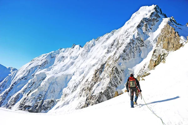 El escalador alcanza la cima del pico de la montaña. Escalada y montañismo concepto deportivo — Foto de Stock