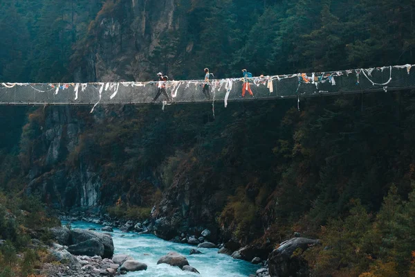 Trekkers attraversando un ponte sospeso nella regione dell'Everest. Parco nazionale di Sagarmatha, Nepal . — Foto Stock