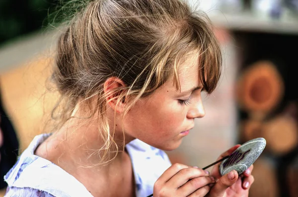 Ung flicka konstnär måla med oljefärger på sten — Stockfoto