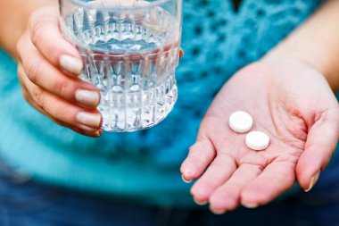 tıbbi ilaçlar ve bir bardak su içinde kadınların elleri