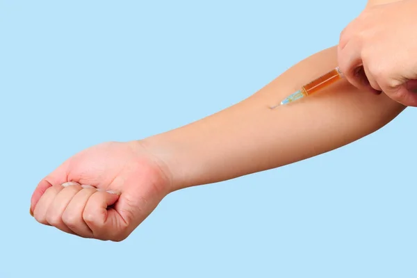 Primer plano de la mano, dando la vacunación al paciente usando una jeringa con medicamentos marrones. Inyección estéril en el brazo . — Foto de Stock