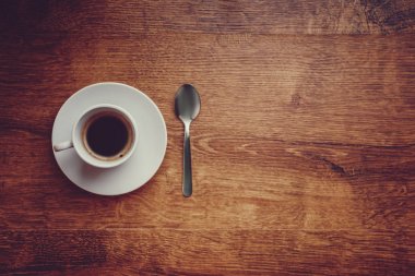beyaz daire ve çay kaşığı koyu kahverengi ahşap arka plan üzerinde siyah kahve ile beyaz Kupası Üstten Görünüm