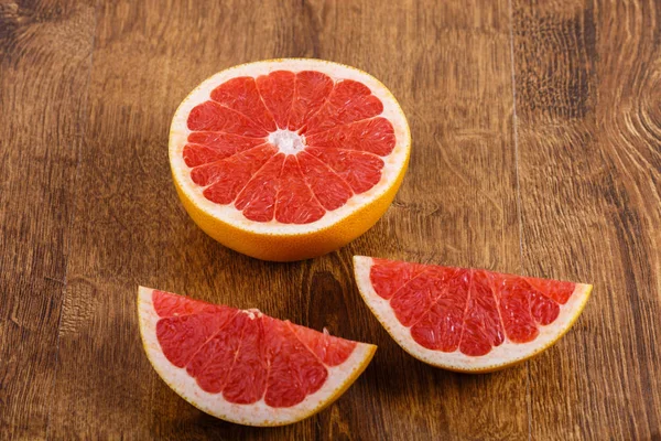 Três pedaços de toranja fatiada na mesa de madeira — Fotografia de Stock