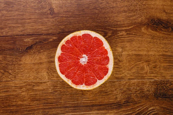 Uma fatia suculenta vermelha de toranja na mesa de madeira — Fotografia de Stock