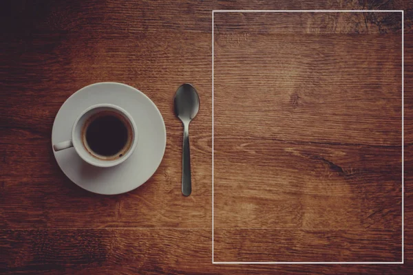 Vista superior de la taza blanca con café negro sobre un platillo blanco y cucharadita sobre fondo de madera marrón oscuro —  Fotos de Stock