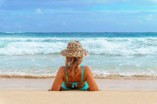 Chica en un sombrero de paja relajarse en la playa de arena y mirando al mar tormentoso — Foto de Stock