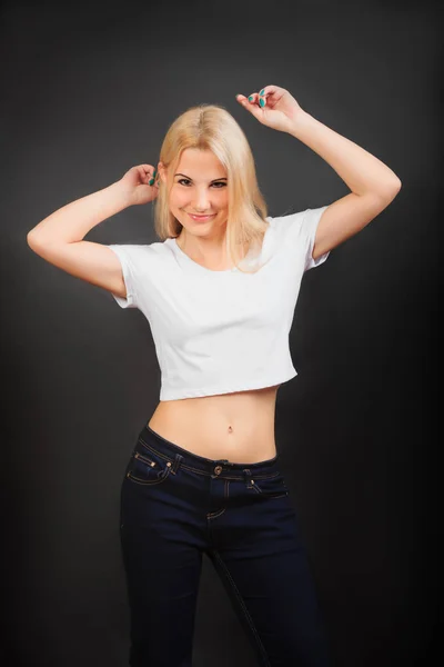 Leuk model meisje in witte korte t-shirt en jeans poseren op zwarte achtergrond — Stockfoto