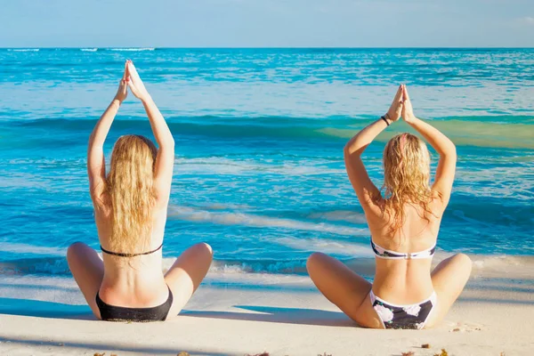Zwei Mädchen machen Yoga-Posen auf dem karibischen Meer — Stockfoto