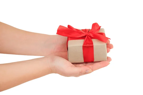 Presentation of gift, female hands giving a gift wrapped with red ribbon on white background top view Stock Photo