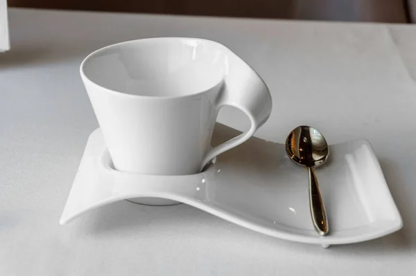 Белая чашка с местом для текста на белой тарелке с чайной ложкой — стоковое фото