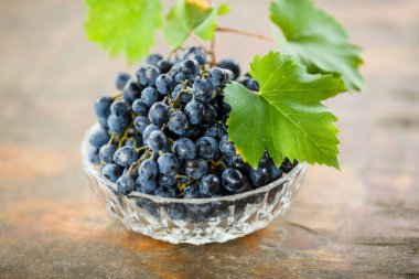 taze sulu olgunlaşmış üzümler beyaz bir kase şarap yapım yeşil yaprakları ile