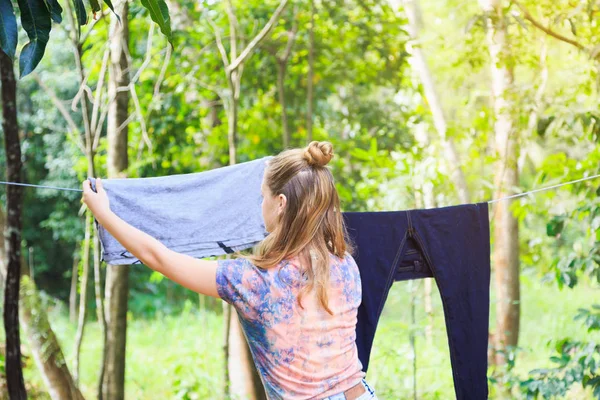 Молодая белая девушка вывешивает одежду, чтобы просушить после стирки — стоковое фото