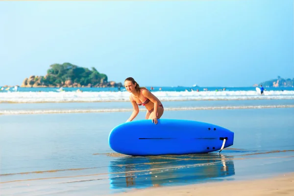 Weißes blondes Surfermädchen mit Surfbrett fährt aufs Meer — Stockfoto