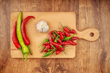 Kırmızı ve yeşil biber ve sarımsak koyu kahverengi ahşap masa üzerinde hafif kahverengi ahşap tahta üzerinde