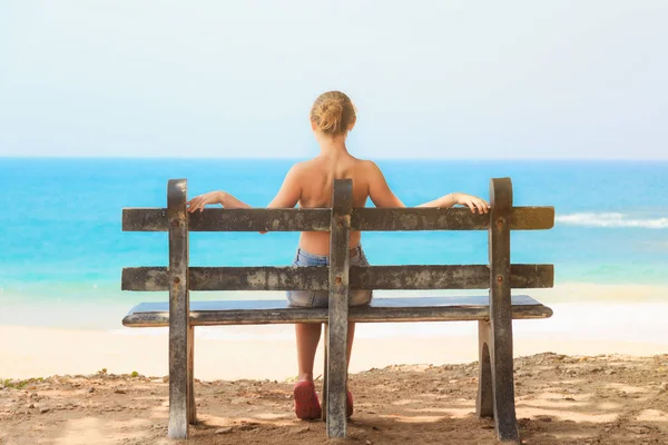 Joven chica blanca sentada sola en un banco de madera en verano — Foto de Stock