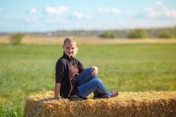 美丽的女孩坐在干草堆上 — 图库照片
