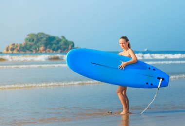 Beyaz sarışın sörfçü kız holding sörf tahtası denize gidiyor