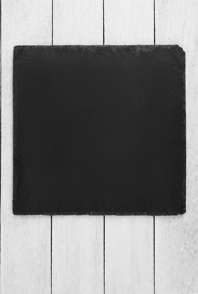 Zwarte leisteen bord op houten achtergrond — Stockfoto
