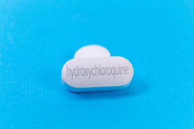 Sıtma tedavisi için hidrokloroksin hapı ve mavi arka planda COVID 19 Corona virüsü için potansiyel yeni ilaç tedavisi. Koronavirüs için terapi.