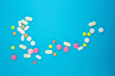 Mavi arka planda tıbbi renkli hapların dağılması