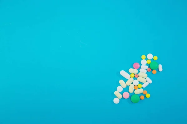 Haufen bunter Pillen auf blauem Hintergrund — Stockfoto