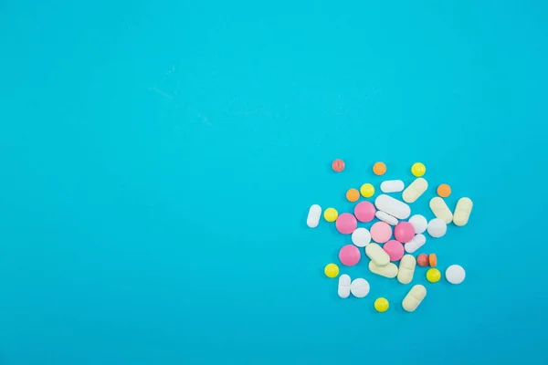 Tas de pilules colorées sur fond bleu — Photo