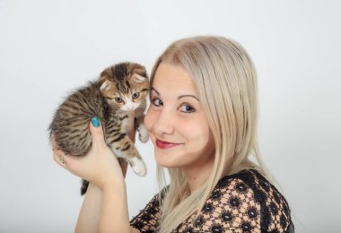 Genç kadın küçük İskoç kedi yavrusunu elinde tutuyor. Yakından.