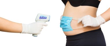 Hamilelik ve Covid19, hamile kadının sıcaklığını kablosuz kızılötesi temassız termometre tabancasıyla ölçüyor. Beyaz arka planda.