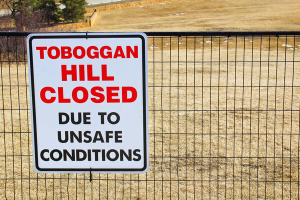 Toboggan hill closed sign posted in a public park once all the snow has melted
