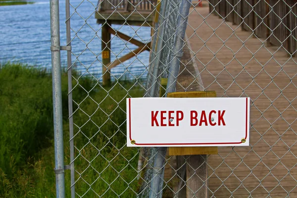 Een houden terug een keten-link fence aanmelden — Stockfoto