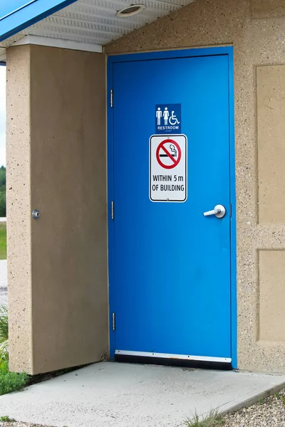 La puerta de un baño multisexual con una señal de no fumar — Foto de Stock