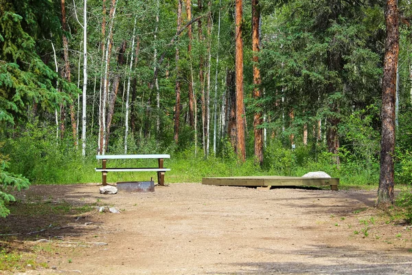 Een camping met een picknicktafel, vuur ring en platform van de tent — Stockfoto