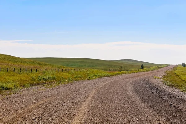 Bir çakıl yol Alberta tarım arazileri ve tepeler — Stok fotoğraf