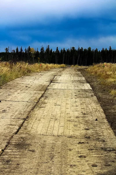 Arka planda yaklaşan bir fırtına olan bataklık mat yol — Stok fotoğraf