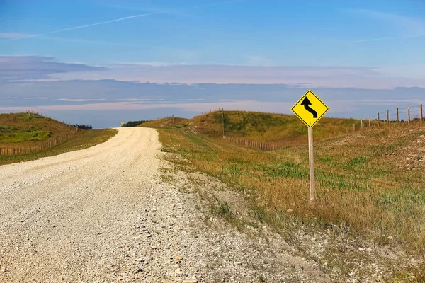 Bir eğri öncesinde uyarı işareti yanında bir ülke yolunda — Stok fotoğraf
