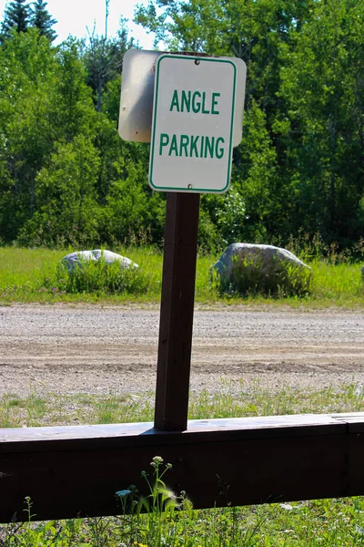 Una señal de estacionamiento de ángulo verde con árboles en el fondo —  Fotos de Stock