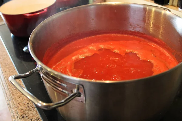 Una olla de salsa de tomate reduciendo en la estufa — Foto de Stock