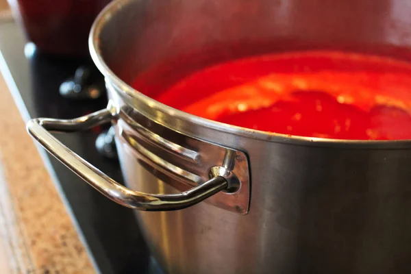Un primer plano de la manija de una olla de salsa de tomate — Foto de Stock