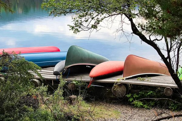 Canoes pulled up on a dock with reflective water — Stock Photo, Image