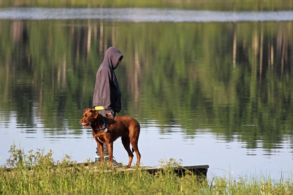 Um rapaz numa doca com o seu cão — Fotografia de Stock