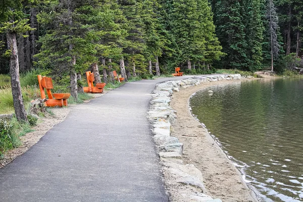 Un camino bordeado de bancos de madera junto a una orilla del lago — Foto de Stock