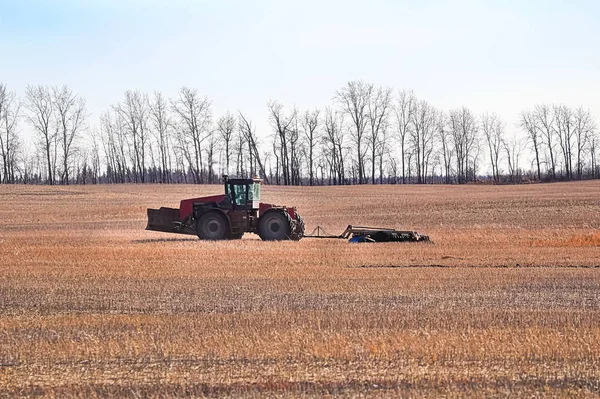 Un tracteur laboure le champ au loin — Photo