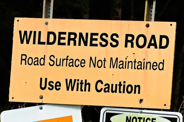 An orange wilderness road, use with caution sign — Stock Photo, Image