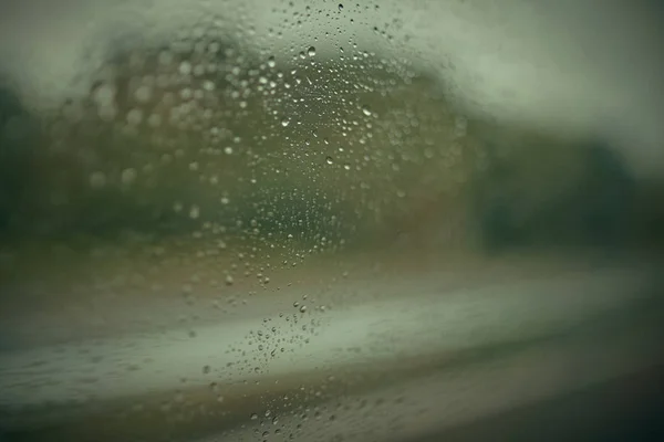 Rain drops on rainy day on outside window glass with blurred edg