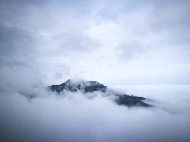 Dağın tepesinde bulutların görünür. Bulutlar dağların kaplı