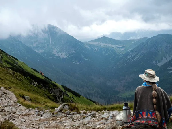 Riposa in montagna. Una donna in un poncho beve il tè da una bottiglia di thermos . — Foto Stock