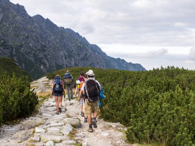 Dağlarda yolda insanlar sırt çantaları ile gider.
