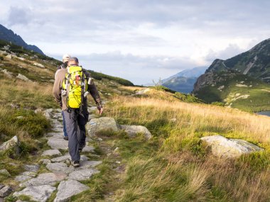 Dağlarda yolda insanlar sırt çantaları ile gider.